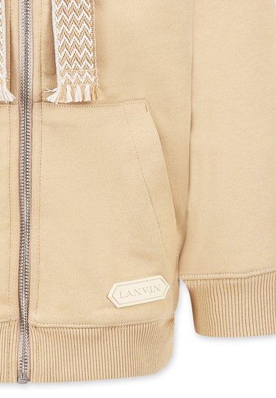 Haut de sweat à capuche zippé beige en matériau doux, avec un cordon de serrage texturé, une poche avant et une étiquette de marque avec "LANVIN" en forme rectangulaire.