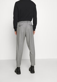 Harmaat, raidalliset housut, joissa on rento istuvuus, joustava vyötärö ja kaksi takataskua. Yhdistetty mustiin nilkkasaappaisiin. Tasainen rakenne.