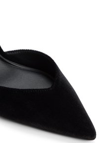 Schwarzer Samt-Pumps mit spitzem Zeh und niedrigem Schnitt, versehen mit einer glatten, strukturierten Oberfläche und einer geschwungenen Kante entlang der Öffnung.