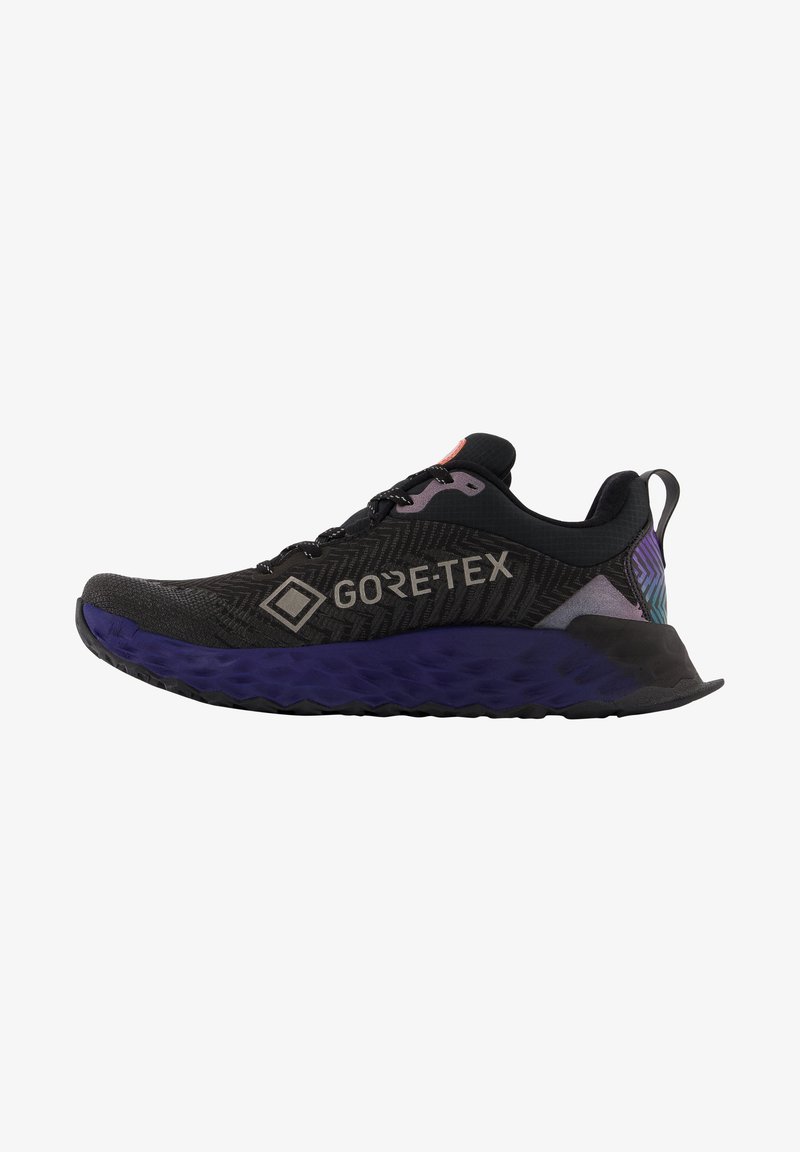 Zapatillas de correr GORE-TEX con parte superior negra y un patrón texturizado, suela púrpura y acentos reflectantes. Diseño ligero para un mejor rendimiento.