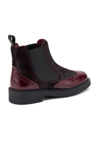 Stivali Chelsea in pelle bordeaux con dettagli in pelliccia, pannelli laterali elastici, decorazioni brogue e suola in gomma nera. Design a profilo basso.