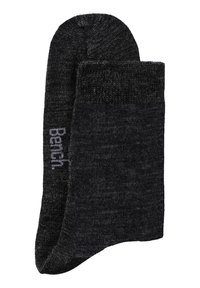 Dunkelgraue Socken aus einem Strickmaterial, mit einem gerippten Bündchen und einem kleinen aufgedruckten Markennamen an der Seite.