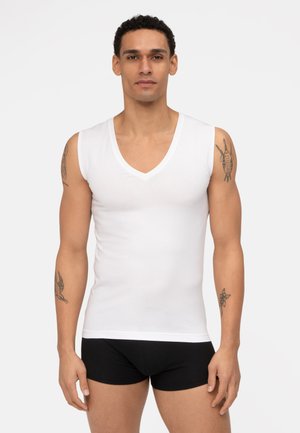 White cotton sleeveless V-neck shirt, smooth texture, fitted design, worn with black shorts, showcasing arm tattoos.