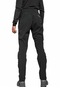 Schwarze Softshell-Hosen mit Reißverschlusstaschen an den Seiten, elastischem Bund und dehnbarem Stoff für Bewegungsfreiheit, mit einem eleganten, ergonomischen Design.