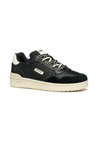 Sneaker noir avec tige en cuir et en daim, semelle en caoutchouc crème et design à lacets. Présente un logo en relief et des accents texturés.