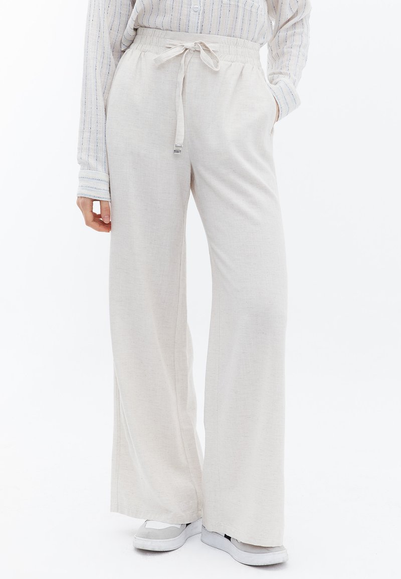 Lichtgekleurde, wijde broek met een elastische tailleband en trekkoord. Gemaakt van zachte stof, met zijzakken en een relaxte pasvorm.