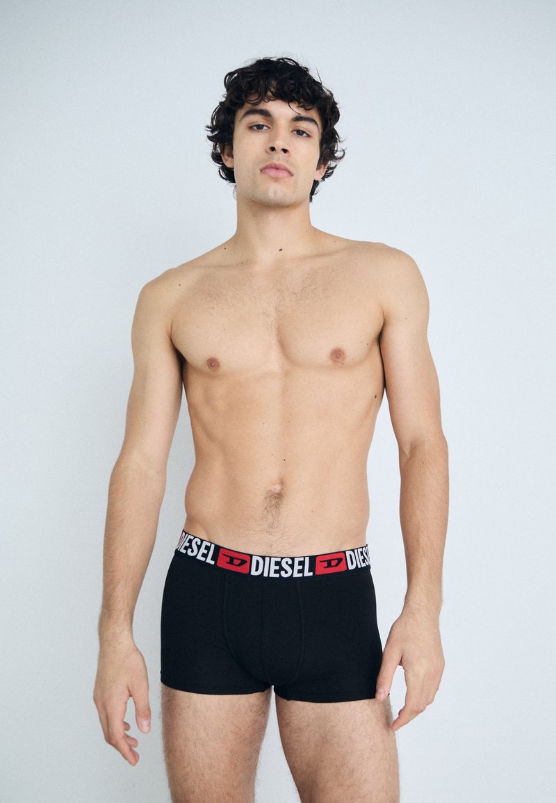 Black boxer briefs with a red and white "DIESEL" logo waistband, made of soft fabric. The design features a form-fitting cut.
