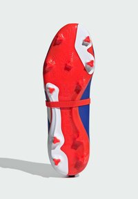 Sole rossa e bianca con borchie prominenti, parte superiore blu. "PREDATOR" è impresso sul lato vicino alla fascia rossa.