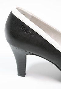 Chaussure à talon haut noire avec garniture blanche et logo Bugatti embossé sur le côté près du talon.