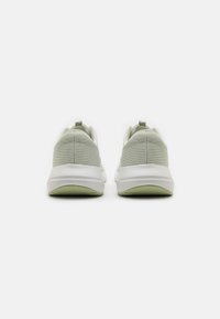Light green fabric sneakers with a textured finish, white soles, and looped pull tabs at the heel. Simple, modern design with minimal accents.