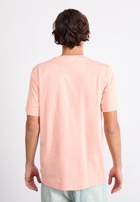 Ljust rosa t-shirt med kort ärm i mjuk bomull, med rund halsringning och rak nederkant. Baksidan är enkel utan mönster eller tryck.