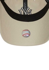 Casquette de baseball avec une couronne couleur beige clair et une visière noire. Présente un logo brodé à l'avant et un motif de baseball à l'intérieur.