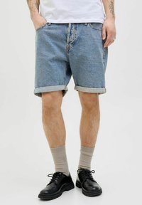 Denim shorts in light blue with turned-up hems, worn with black lace-up shoes and beige socks; features side pockets and a classic fit.