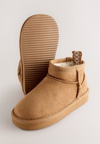 Bottines en daim couleur fauve avec une doublure douce en polaire, dotées d'une semelle en caoutchouc texturée et de détails cousus. Comprennent une boucle décorative au talon.