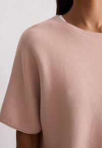 Różowy krótki rękaw dzianinowy top z okrągłym dekoltem, z ribbowanym wzorem i bezszwowymi ramionami. Lekki materiał dla wygody.