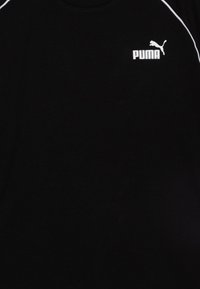 Crna pametna majica s bijelim Puma logotipom na lijevom prsnom dijelu i bijelim obrubom uz rameni šav. Mekana tekstura, okrugli izrez.