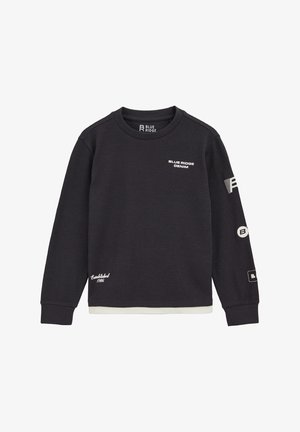 Melna garu piedurkņu džemperis ar teksturētu audumu un apļveida kaklu. Iezīmētas baltas logos uz krūtīm un piedurknēm, kā arī balta akcenta detaļa apakšmalā.