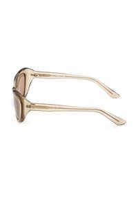 Lunettes de soleil à monture en plastique transparent marron avec des verres arrondis et des branches fines, marquées "GUESS" sur le côté.