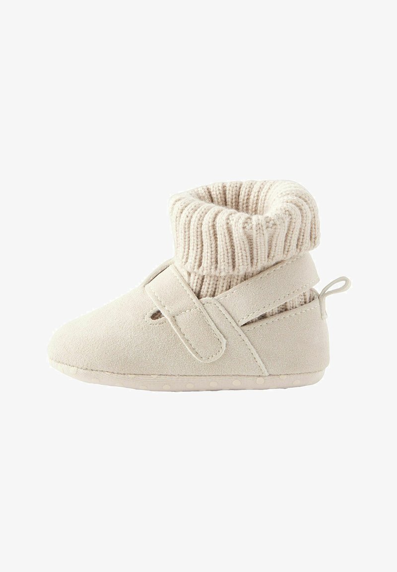 Beige suede bootie with knitted cuff, Velcro closure, and rubber sole with textured dots for grip. Soft and flexible design for comfort.