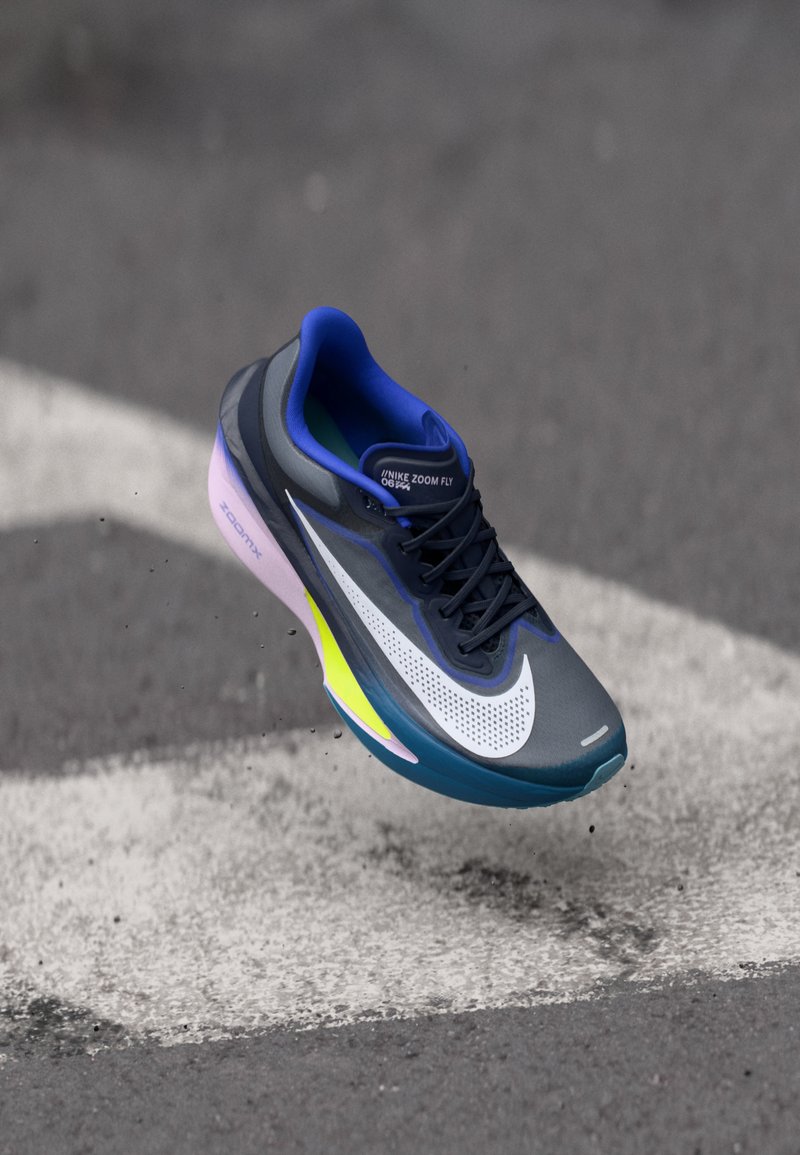 Zapatilla de running Nike Zoom Fly, con una parte superior de malla gris, acentos en azul vibrante y amarillo neón, y una suela acolchada bicolor.