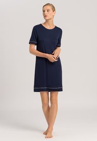Vestido de manga corta en azul marino, confeccionado en una tela suave, con cuello redondo y un ribete de color claro en las mangas y el dobladillo.