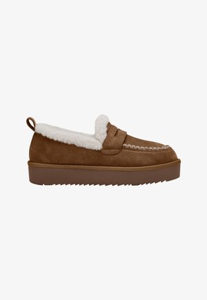 Brun ruskind slip-on mokasin med hvid fleeceforing, tyk sål med rillede bund og en trækflap ved hælen.