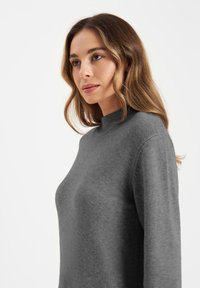 Grijze pullover trui met hoge hals, lange mouwen en zachte textuur. Eenvoudig ontwerp zonder zichtbare patronen of hardwaredetails.