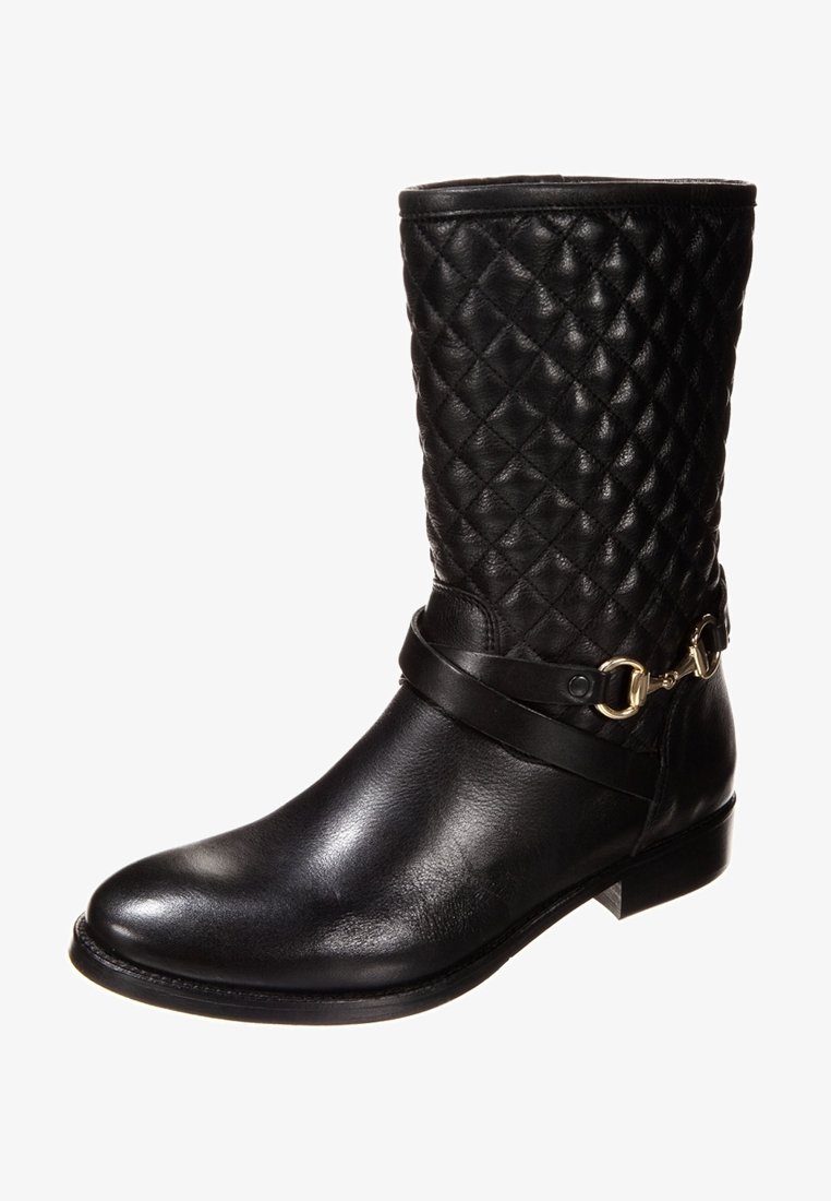 Svart läder ankle boot med en quiltad skaft, platt klack och ett dekorativt band som har en guldtonad spänne. Släta och texturerade ytor.