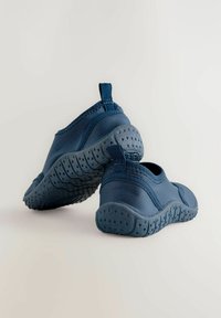 Scarpe slip-on blu con suole in gomma testurizzata. Parte superiore in tessuto liscio, linguetta posteriore e bordi imbottiti per il comfort.