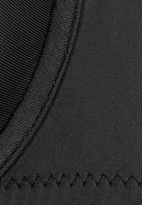 Schwarzer Neoprenstoff mit einer strukturierten Oberfläche. Verfügt über glatte Nähte und Zickzackstich entlang der Kante.