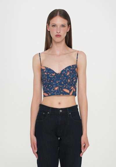 Námořnický crop top s květinovým vzorem v oranžové a zelené barvě. Má špagetová ramínka a výstřih ve tvaru srdce. Spárováno s tmavými džíny.