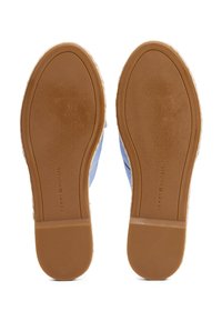 Paire de chaussures slip-on bleu clair montrée par les semelles, avec semelles extérieures en caoutchouc marron et logo "Tommy Hilfiger" sur chaque semelle.