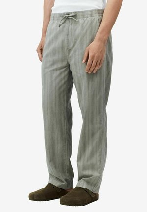 Helle graue, gestreifte, lässig geschnittene Hose mit einem elastischen Bund und Kordelzug. Hergestellt aus einem weichen Material, getragen mit braunen Slippern.