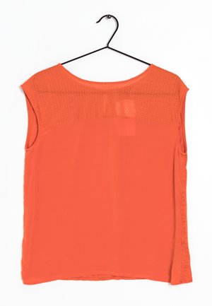 Blusa arancione a maniche corte con un pannello testurizzato sulle spalle, corpo liscio e una vestibilità leggermente ampia, caratterizzata da un orlo curvo.