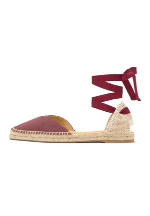 Płaski espadryl z bordowym materiałowym przodem, plecioną podeszwą z naturalnych włókien oraz bordową wstążką wiązaną wokół kostki na białym tle.