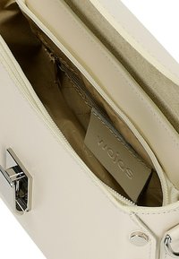 Crème leren clutch met zilveren hardware. Voorzien van een ritsvak met een beige interieur en een label. Platte en rechthoekige vorm.