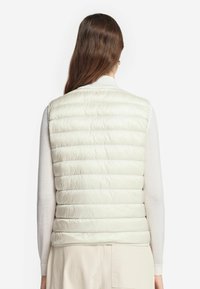Dikke crèmekleurige vest met een gestikte textuur en een hoge kraag, voorzien van een soepele, lichte stof voor isolatie en een getailleerde pasvorm.