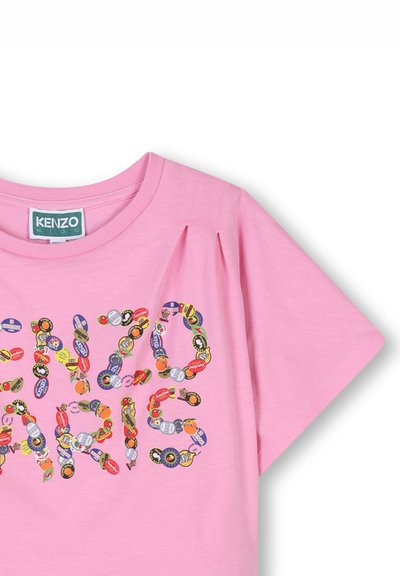 T-shirt rose à manches courtes avec un col rond, ornée d'un imprimé décoratif constitué d'autocollants colorés au motif varié épelant "KENZO PARIS".