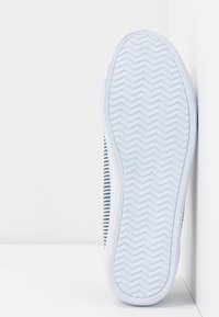 Baskets avec une tige en tissu rayé bleu et blanc. Elles disposent d'une semelle en caoutchouc blanc avec un motif en zigzag pour une meilleure adhérence.