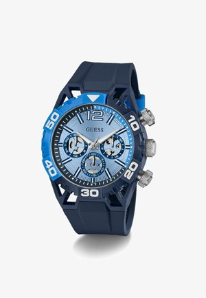 Blue silicone strap watch with a round navy case. Light blue dial features three chronograph sub-dials, silver accents, and bold numerals.