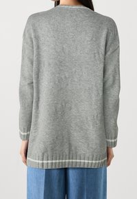 Suéter gris de punto con textura estampada, mangas largas y puños acanalados con acentos de rayas blancas en el dobladillo.