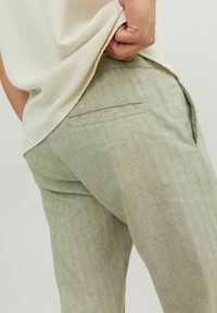 Ljust gröna linnebyxor med en slät textur, med en bakficka och subtila sömdetaljer. Bärs under en lös passformad topp.