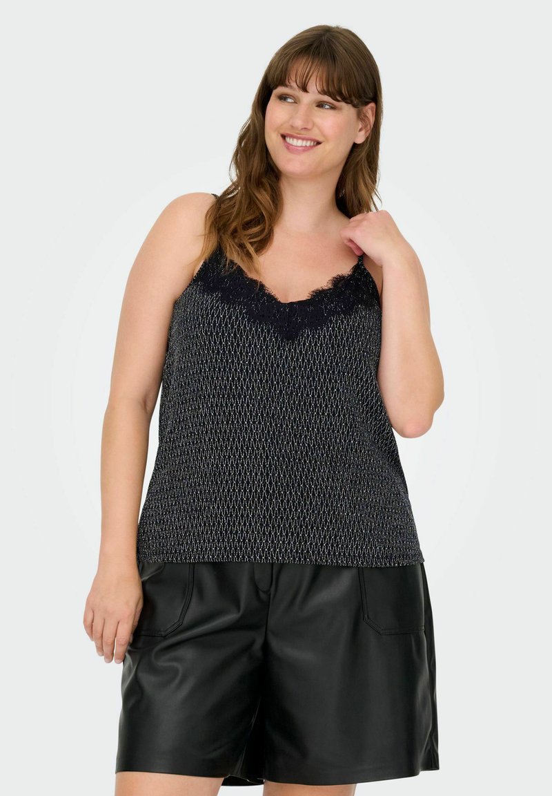 Camiseta de tirantes con estampado en blanco y negro y encaje en el escote, combinada con pantalones cortos de cuero negros. Textura suave con tirantes ajustables.