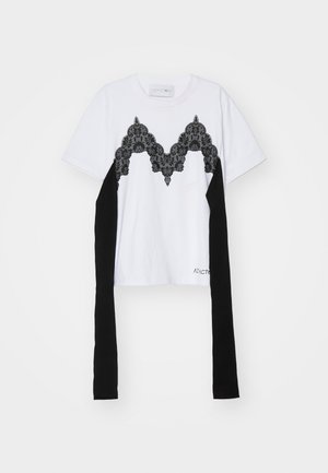 White short-sleeve T-shirt with black lace pattern on chest, black side panels, and long black fabric accents extending from sleeves.