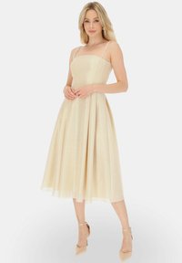 Sukienka do kolan w jasnym odcieniu złota, z regulowanymi cienkimi ramiączkami, dopasowanym górnym krojem i rozkloszowanym dołem. Wykonana z teksturowanej tkaniny o subtelnym połysku.
