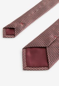 Burgundy tie with a textured geometric pattern, featuring a solid smooth lining at the tip. Finished edges with a narrow shape.