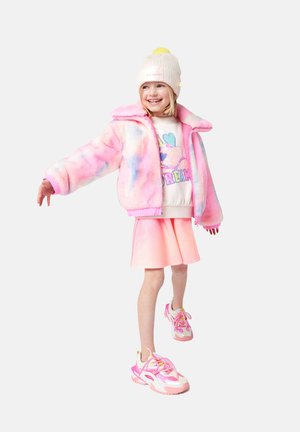 Veste courte floue, rose pastel et bleu ; sweat-shirt graphique blanc ; jupe rose brillante ; baskets colorées avec des accents et des lacets roses.