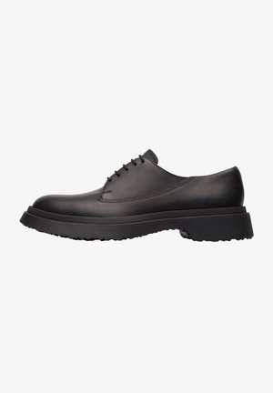 Chaussures en cuir noir au fini lisse, à bout arrondi, avec de fins lacets et une semelle en caoutchouc épaisse et texturée. Design minimaliste.