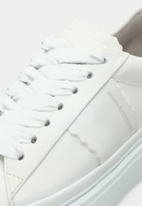 Άσπρο δερμάτινο αθλητικό παπούτσι με σχεδιασμό στρογγυλεμένης μύτης, υφασμένα κορδόνια και γκρι λεπτομέρειες. Διαθέτει λευκή λαστιχένια σόλα και διακριτικό λογότυπο.