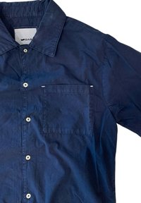 Camicia blu navy con bottoni realizzata in cotone, con colletto a punta, tasca frontale sul petto e bottoni a pressione in madreperla. Tessuto liscio.